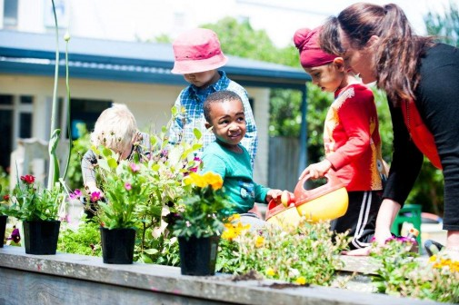 A group of children working with a kaiako in the garden