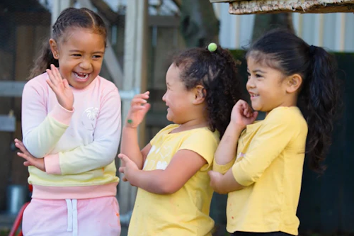 Three children laughing together outside.