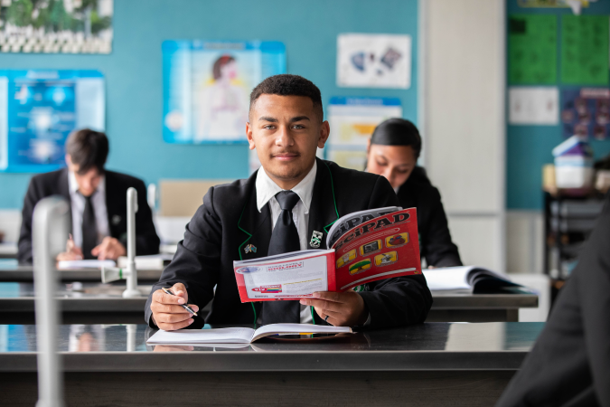 A student working with a textbook in a classroom.