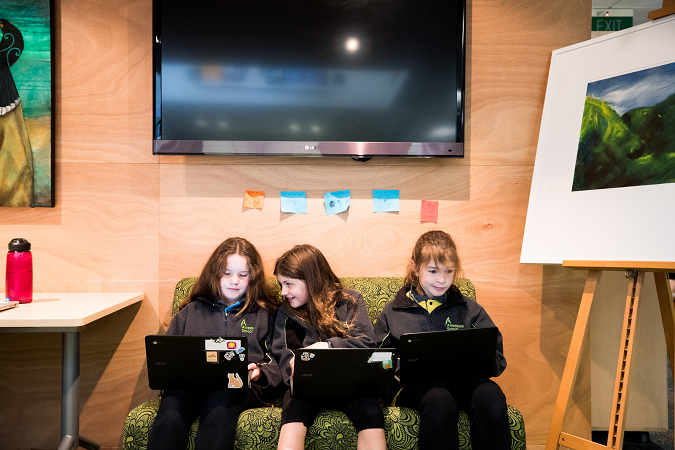 Three tamariki studying with their chromebooks while they sit on the couch.