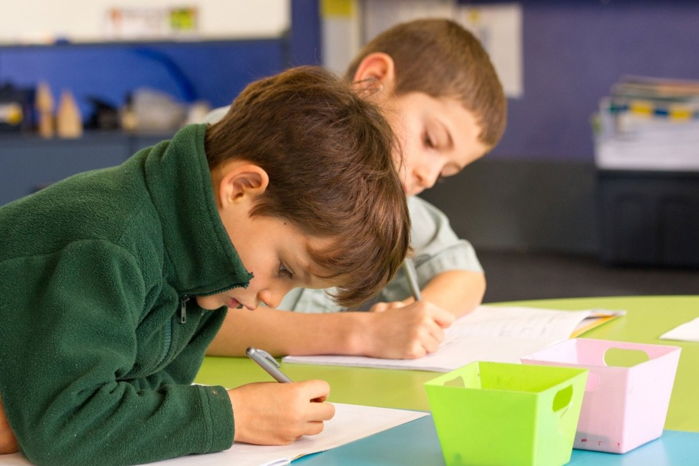 Two students sitting and drawing in a class.