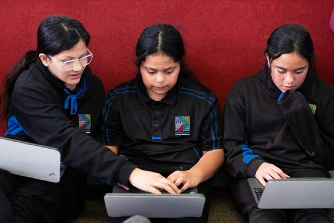 Three girls sitting on floor working on laptops.