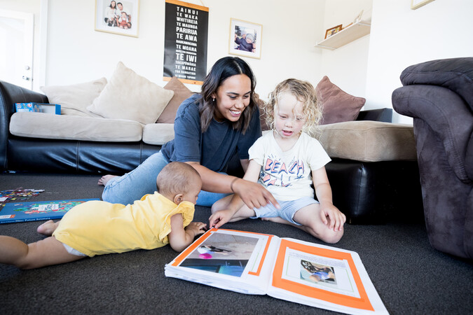 Teacher and two children on the floor reading a book