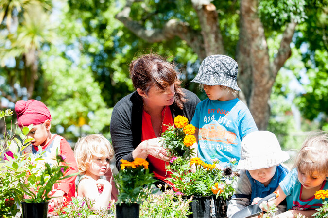 Lady in a garden planting flowers with the children