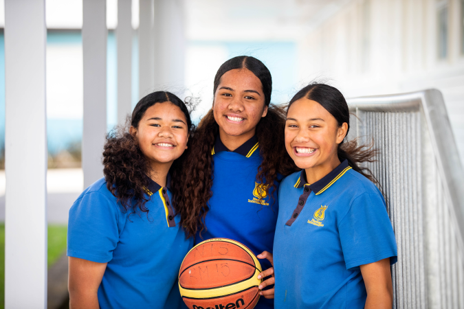 Three girls standing with basketball.