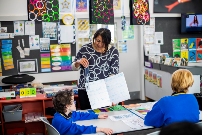 Kaiako teaching ākonga at the front of a classroom.