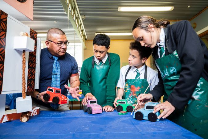 Pupils standing next to teacher explaining project.