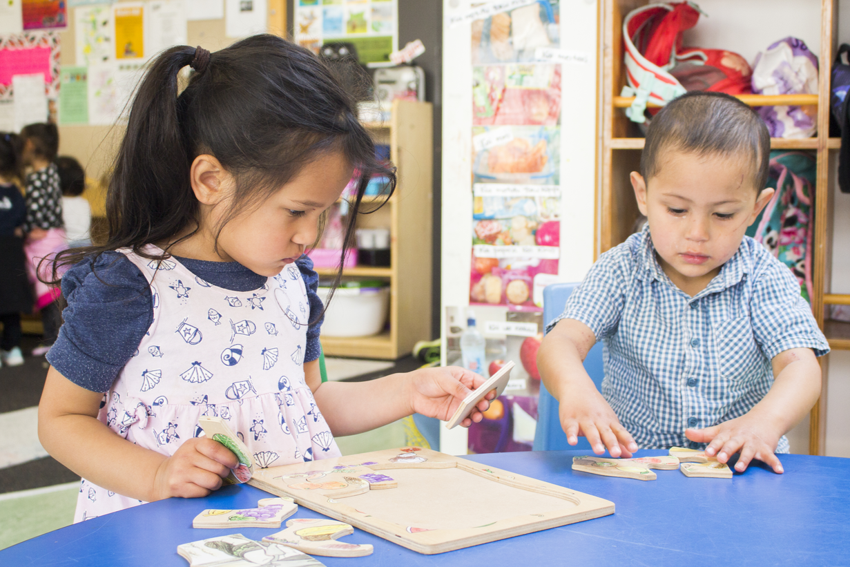 two children doing a puzzle together at a table