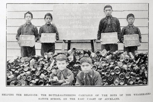 Black and white photo of boys from wharekahika native school in front of bottles. 