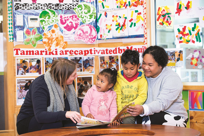 Children gather around as their Kaiako reads them a picture book 