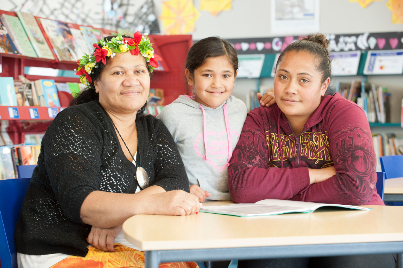 Whānau gathered at the table smiling at the camera 