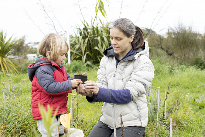 Young ākonga and Whaea holding a pre-potted tree together