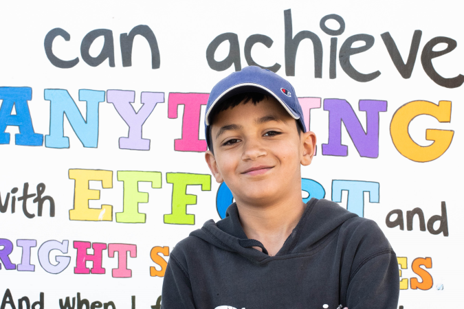 Boy standing folded arms in front of a board.