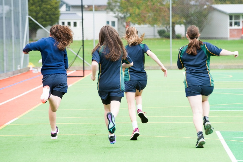 Four teenage girls are running across the courts.