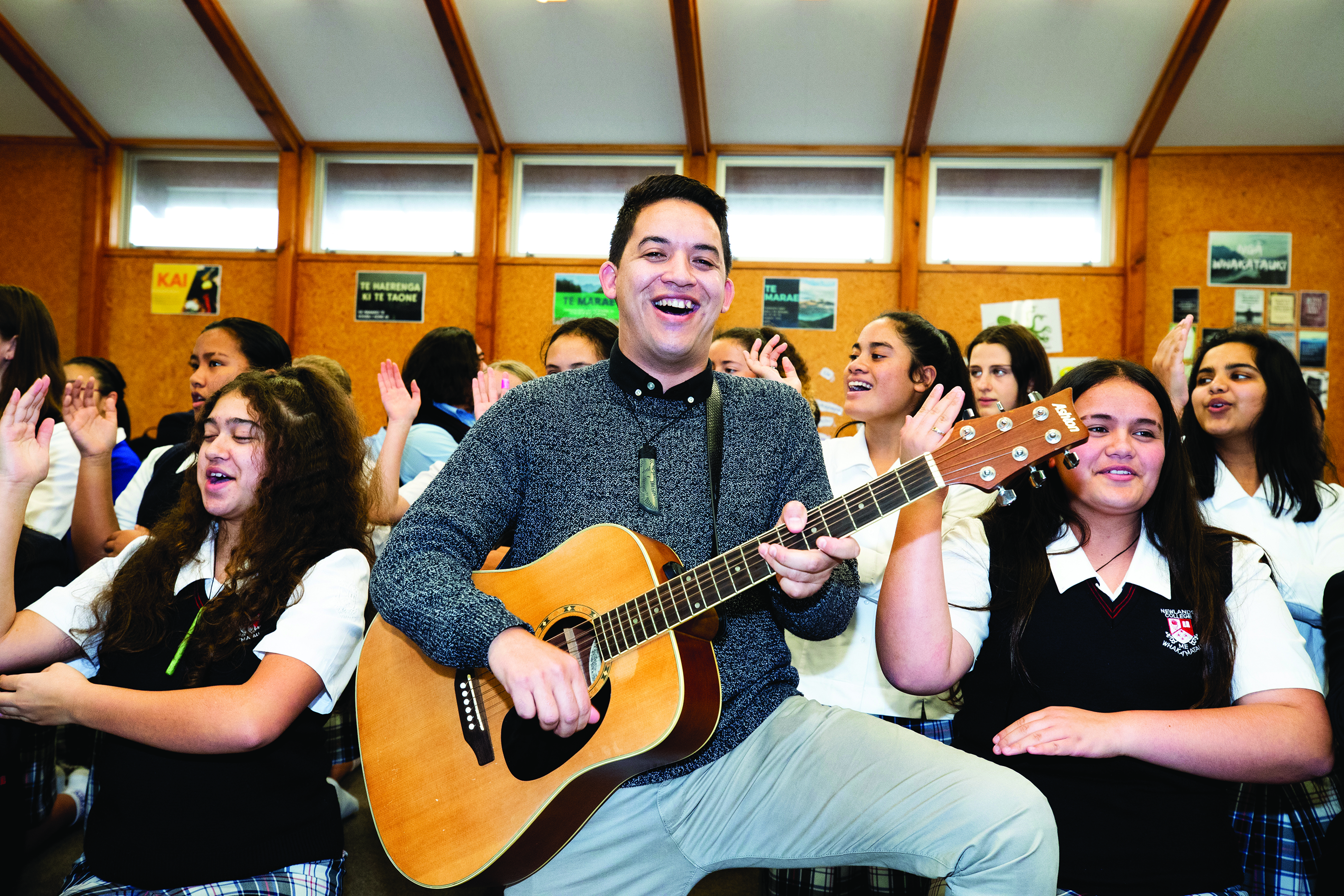 Man with guitar playing in front of students