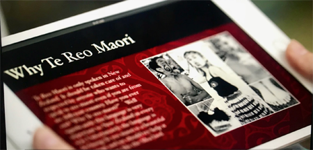 A tablet showing a webpage with a heading that reads, “Why te reo Māori?”, text, and photographs of tamariki in kapa haka clothes.