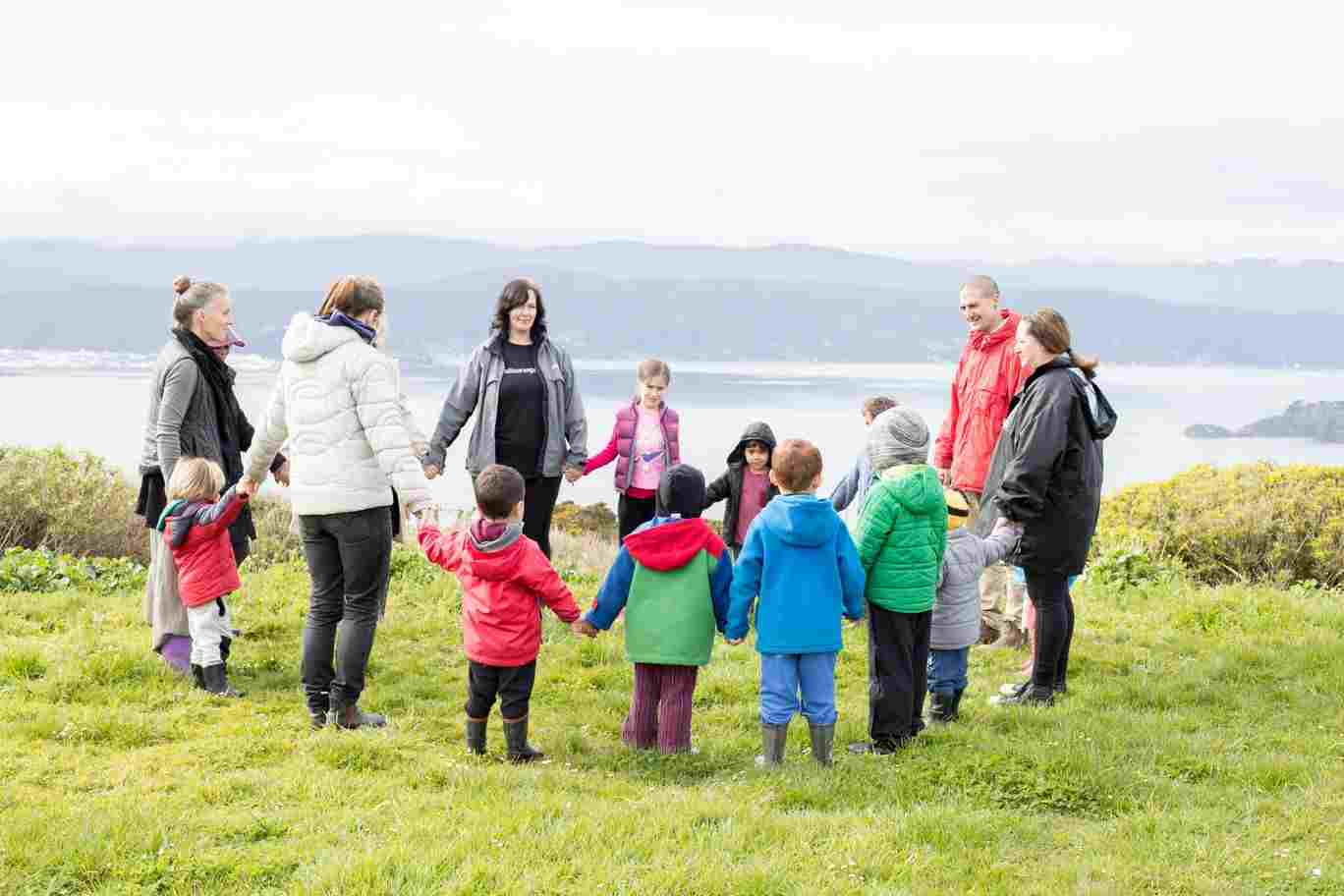 A group of kaiako and children as a community of learning holding hands.