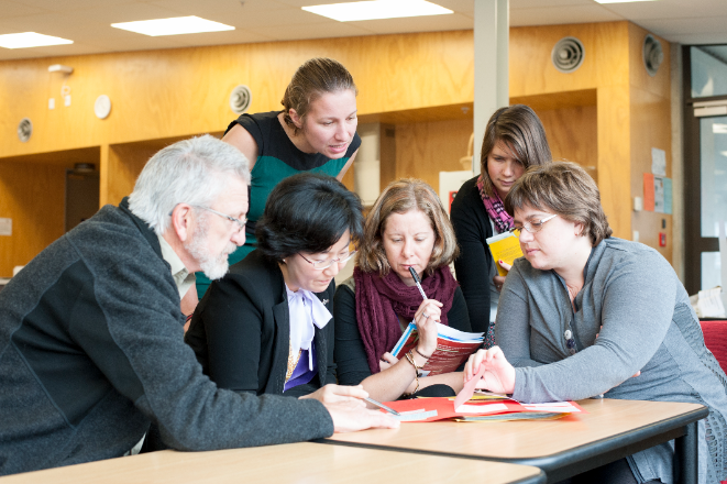 A group of kaiako gathered around a table analysing a resource.