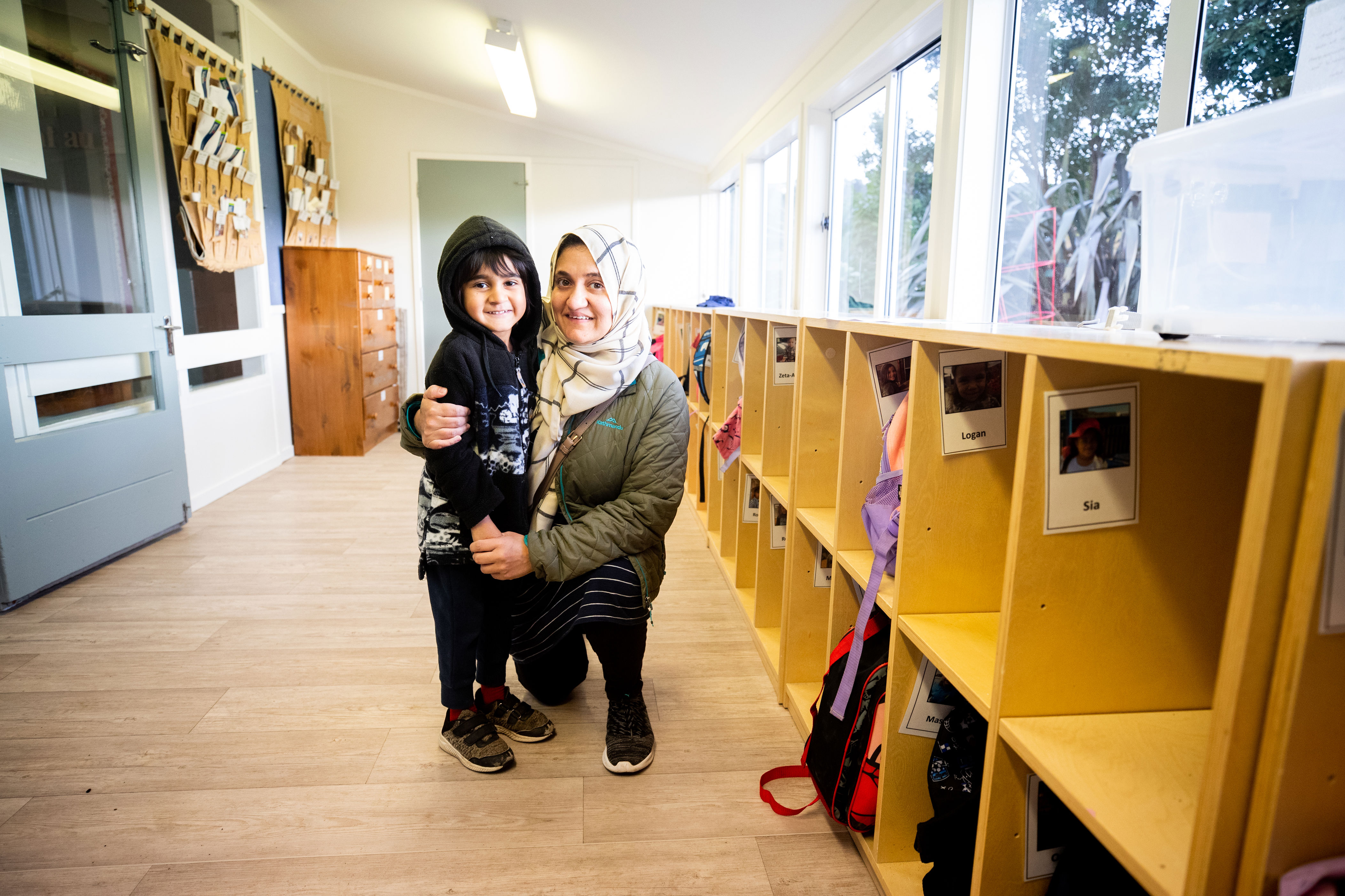 Parent kneeling down with their arm around a child.