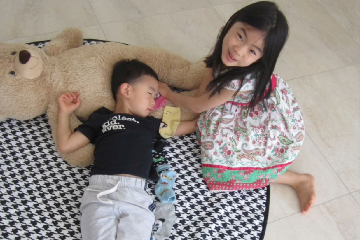 kids playing with socks while lying on a teddy bear 