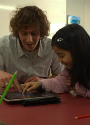 Kaiako and akonga work together on an ipad.