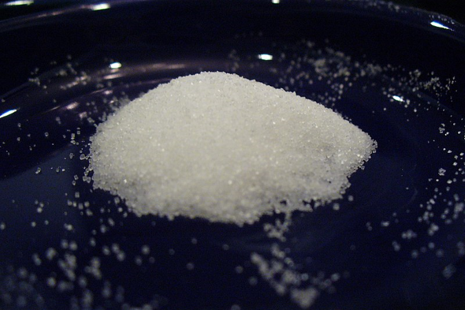 Pile of salt on a black surface.