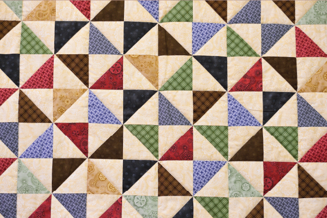 A multicoloured quilt pattern made of triangles.
