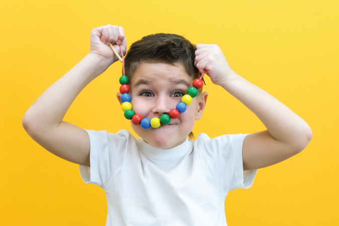 A boy showing a necklace of colourful beads in front of him.