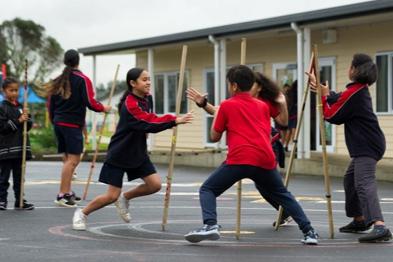 Children playing a stick game in the school yard.