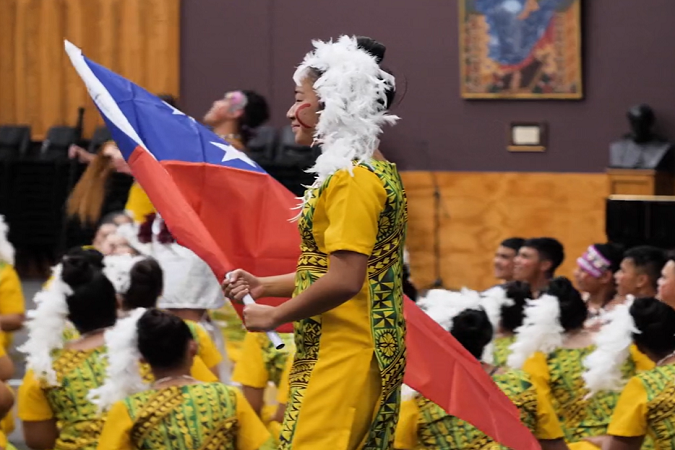 Students dressed in traditional attire and one student holding the Samoan flag.