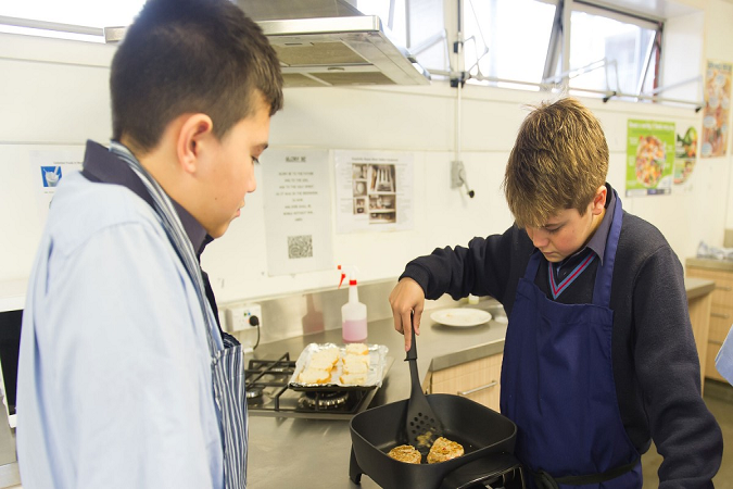 Two students cooking fritters together. 