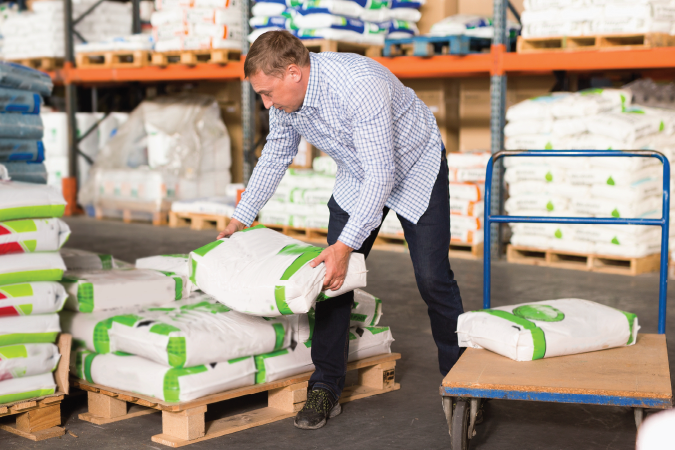 A man stacking bags of goods onto a pallet.