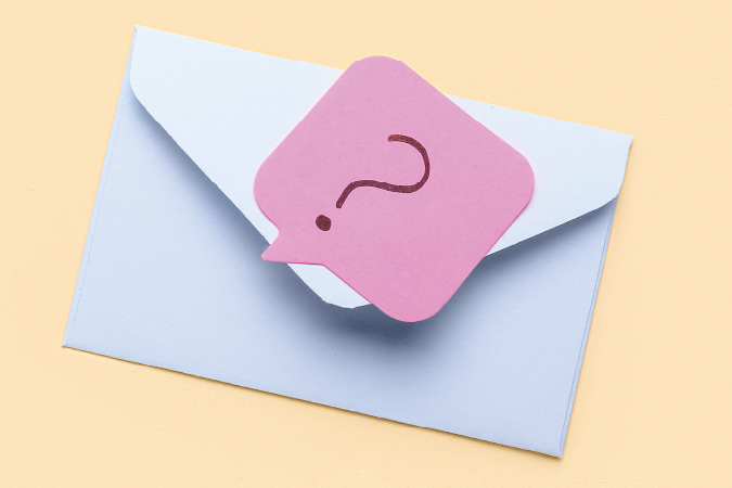 Envelope with a pink slip of paper with a question mark on it. 