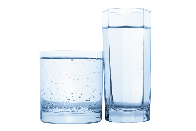 A short and wide glass cup adjacent a tall and skinny glass cup.