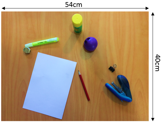 Desktop measuring 54 by 40 centimetres. On top of the desk is a piece of paper, stapler, clip, sharpener, glue stick, pencil, and highlighter. 