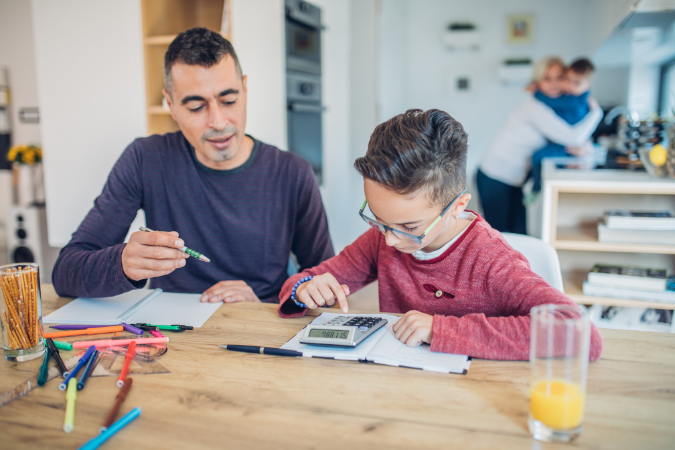 A parent helps their child with their maths homework.