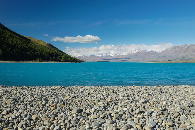 A photograph of a lake with mountains and a stone path. 