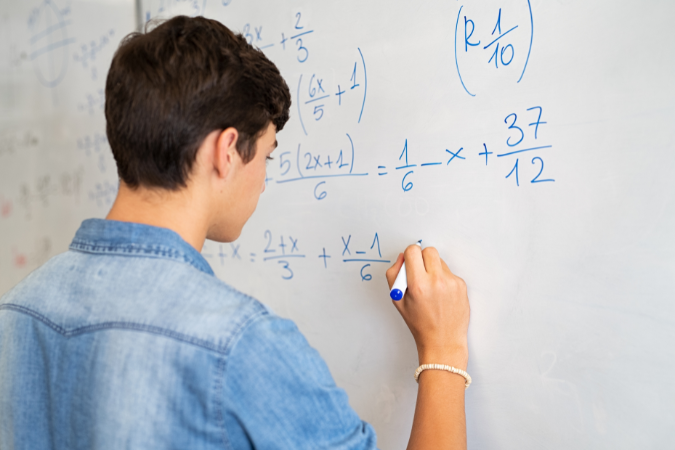 Student solving mathematical equations on the whiteboard.