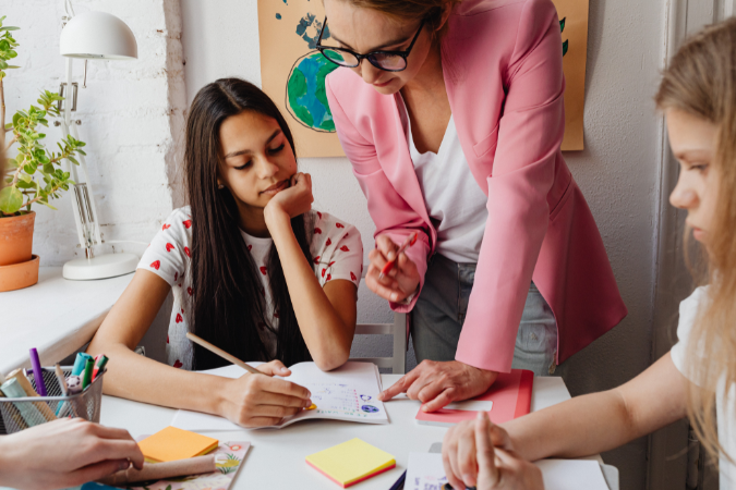 An adult helps students with their schoolwork.