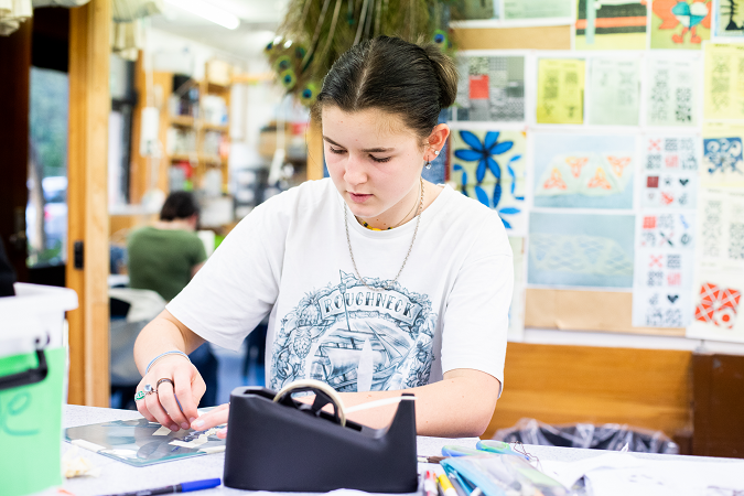 A senior student sits at their desk, crafting.