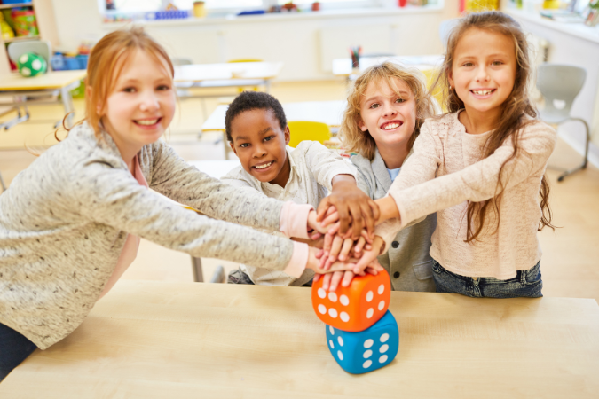 Four children are playing with two large dice.