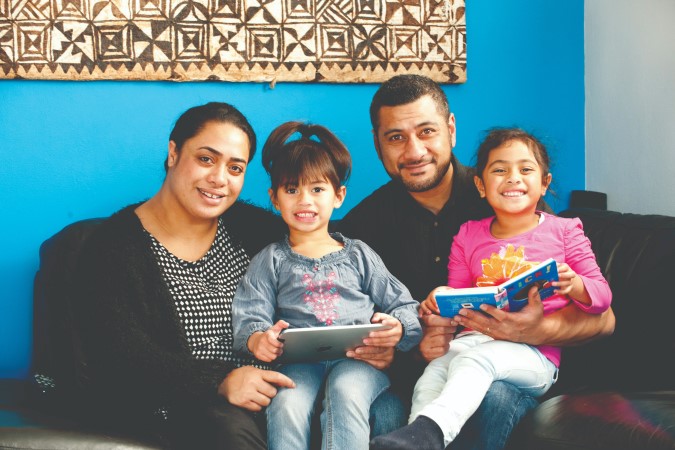 A family sat on a couch together, reading.