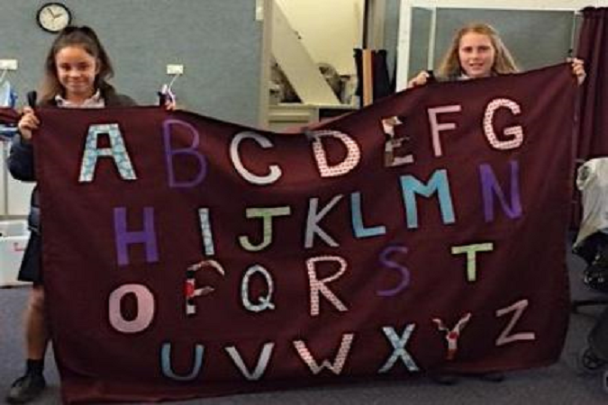 Students holding their sunshade deck curtain with letters.