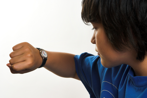 A child looking at the time on their watch.