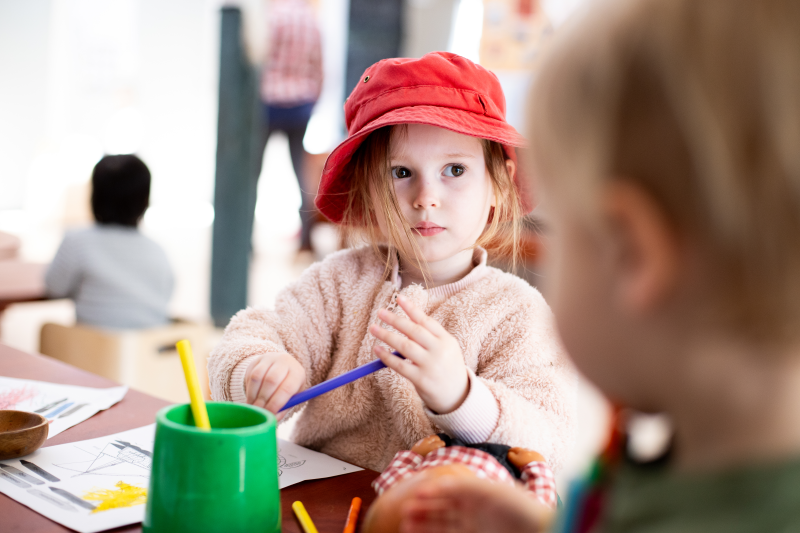 A young girl colouring at a table.