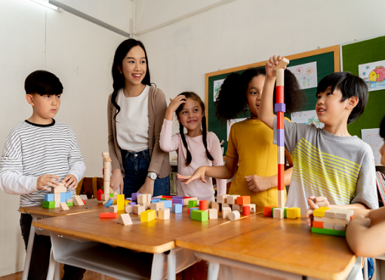 A teacher and a group of children are working on a project in a classroom.