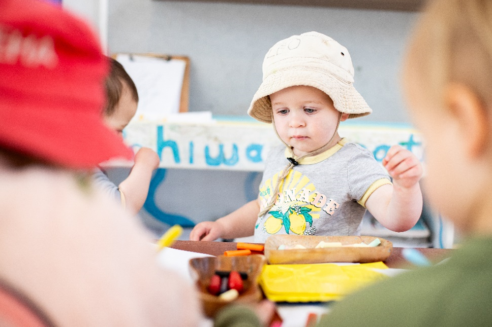 A young child selecting crayons and chalk at a table.