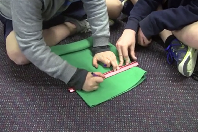 Two children measuring fabric.