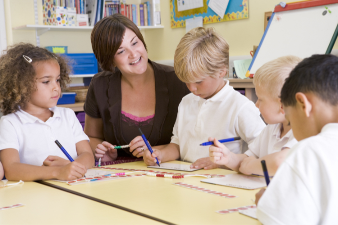 A teacher and children sitting in a circle working on a task together.