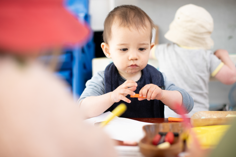 A young boy using crayons to colour at a table.